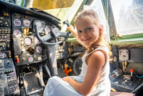 Young girl exploring airplane cockpit and holding flight controls. First aviation experience encourages childhood curiosity, learning and career dreams
