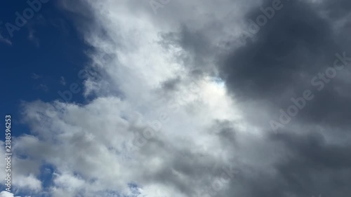 Dramatic dark storm clouds swallowing and covering soft white clouds in a contrasting blue sky with strong copy space
