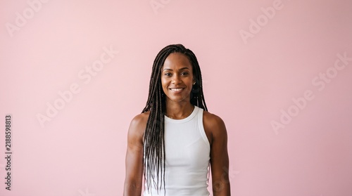 Young African American Woman with Braids Smiling Confidently Against a Soft Pink Background