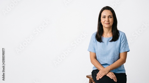 Professional Woman Sitting Confidently in a Studio with a White Background