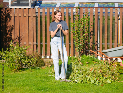 Smiling woman with garden rake during backyard cleanup