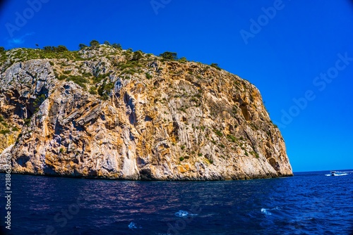 Принти на полотні Rugged cliff face drops dramatically into deep blue ocean