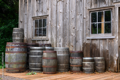 Rustic wooden barrels stacked against an old wooden barn