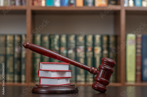 фотографія A judge's gavel and miniature symbolic books against the backdrop of a bookshelf