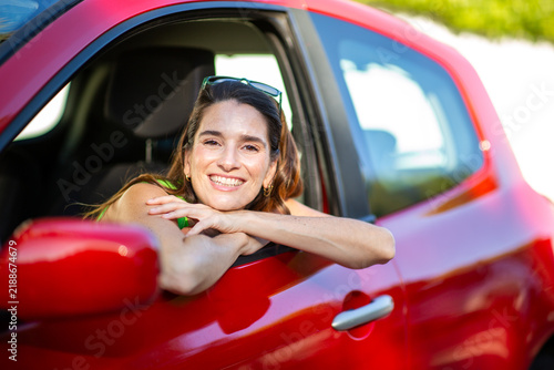Smiling woman leaning from red car window