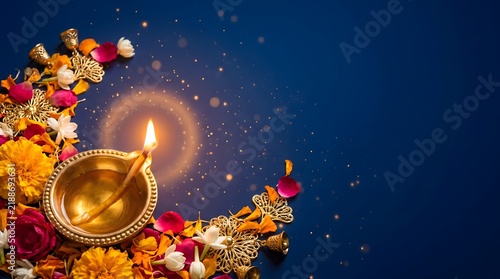 Traditional diwali oil lamp diya decorated with vibrant flowers and sparkles on a deep blue background for celebration