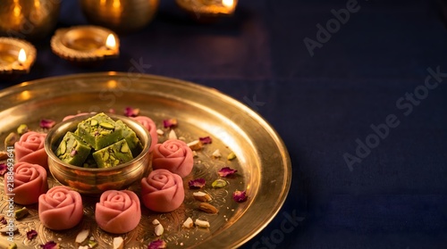 A beautiful brass plate filled with traditional indian sweets and dry fruits for the festive celebration of diwali holiday
