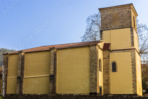 Bright yellow building of the Sanctuary of the Holy Christ of the Agony against a clear blue sky. Limpias, Cantabria, Spain.