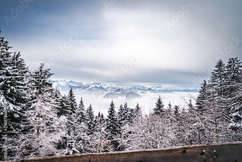 Fotografie Winter landscape with a wooden railing overlooking a snow covered forest and mou