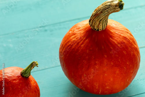 Small and large Hokkaido pumpkins on blue-painted wooden boards.