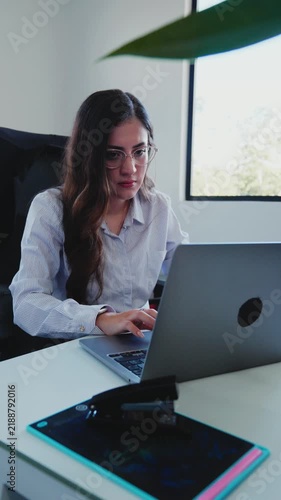 Focused young businesswoman working on laptop computer at her office desk