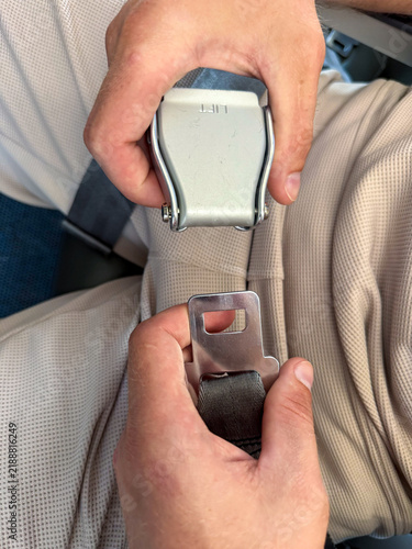 Принти на полотні Hands of a person fastening a silver seatbelt buckle to a black seatbelt in a ve