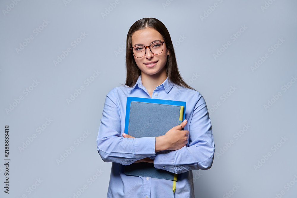 Obraz premium Young female student holding notebook folder standing looking at camera studio