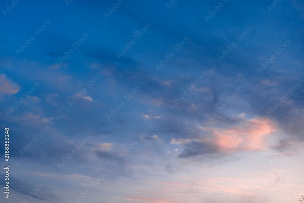 Fototapeta premium Soft evening sky with pale pink clouds. Gentle sunset light reflects on the scattered vapor. Calm twilight blue atmosphere.