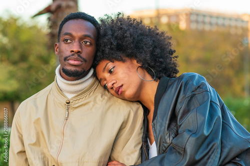 Фотография Loving young Black couple embracing tenderly in a green park at sunset