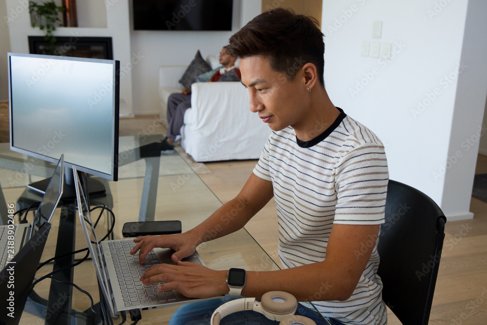 Fototapeta premium Male housemates working and relaxing in living room with laptop, monitor, headphones, smartwatch