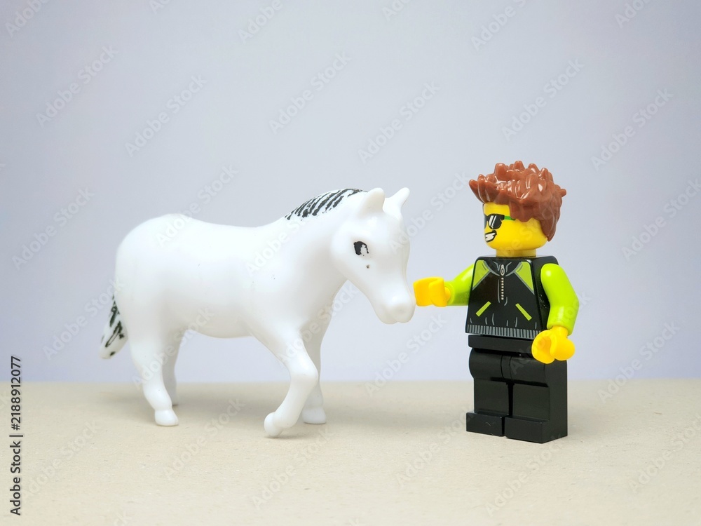 Fototapeta premium Indonesia - December 1, 2023 : Mini toy figure of people at table with blurred background. Miniature photography concept design. Horse Jockey concept.