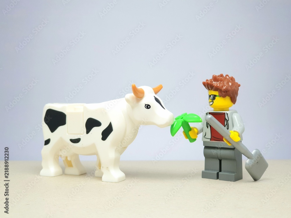 Obraz premium Indonesia - December 1, 2023 : Mini toy figure of people at table with blurred background. Miniature photography concept design. Farmer give green leaves plant.