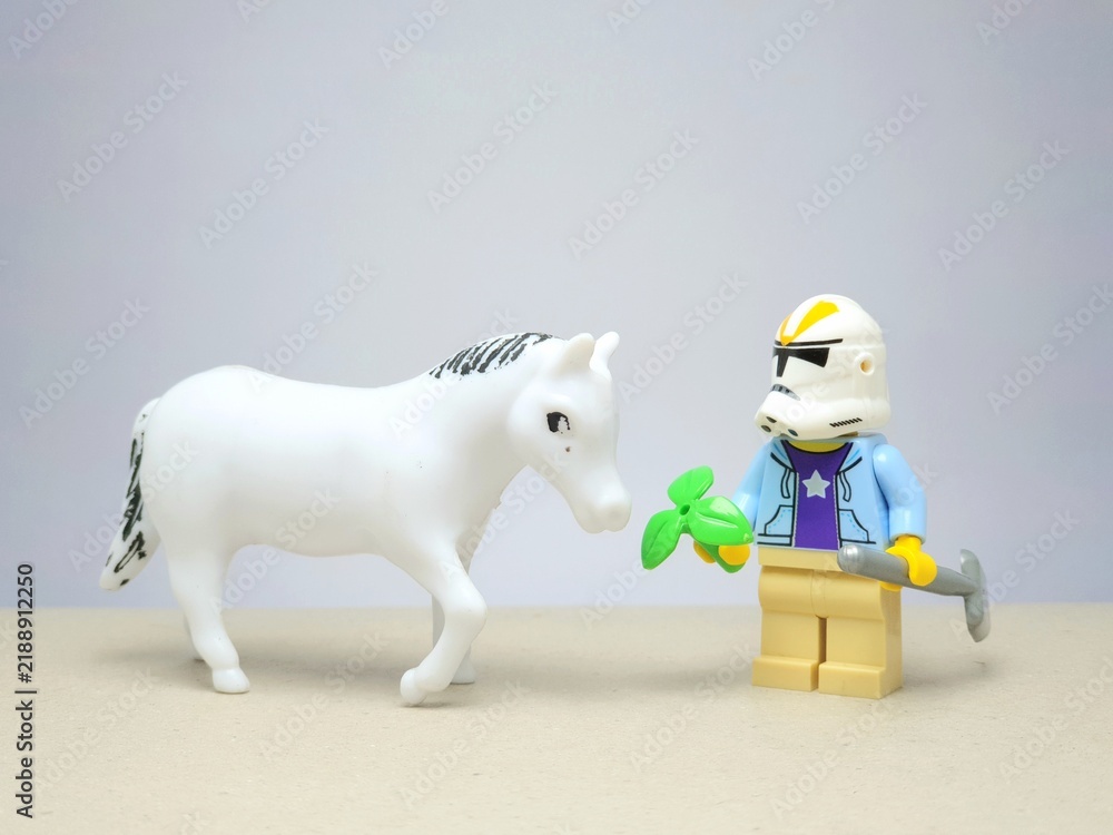 Obraz premium Indonesia - December 1, 2023 : Mini toy figure of people at table with blurred background. Miniature photography concept design. Farmer give green leaves plant.