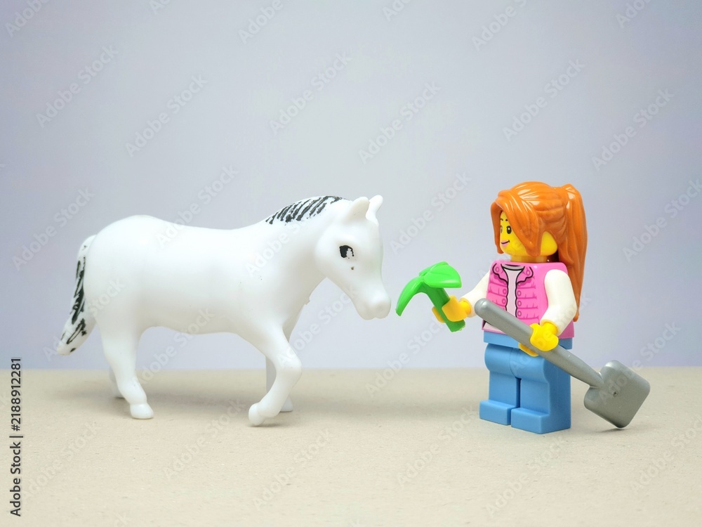 Obraz premium Indonesia - December 1, 2023 : Mini toy figure of people at table with blurred background. Miniature photography concept design. Farmer give green leaves plant.