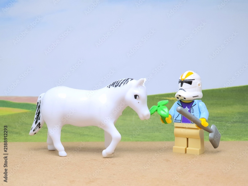 Obraz premium Indonesia - December 1, 2023 : Mini toy figure of people at table with blurred background. Miniature photography concept design. Farmer give green leaves plant.