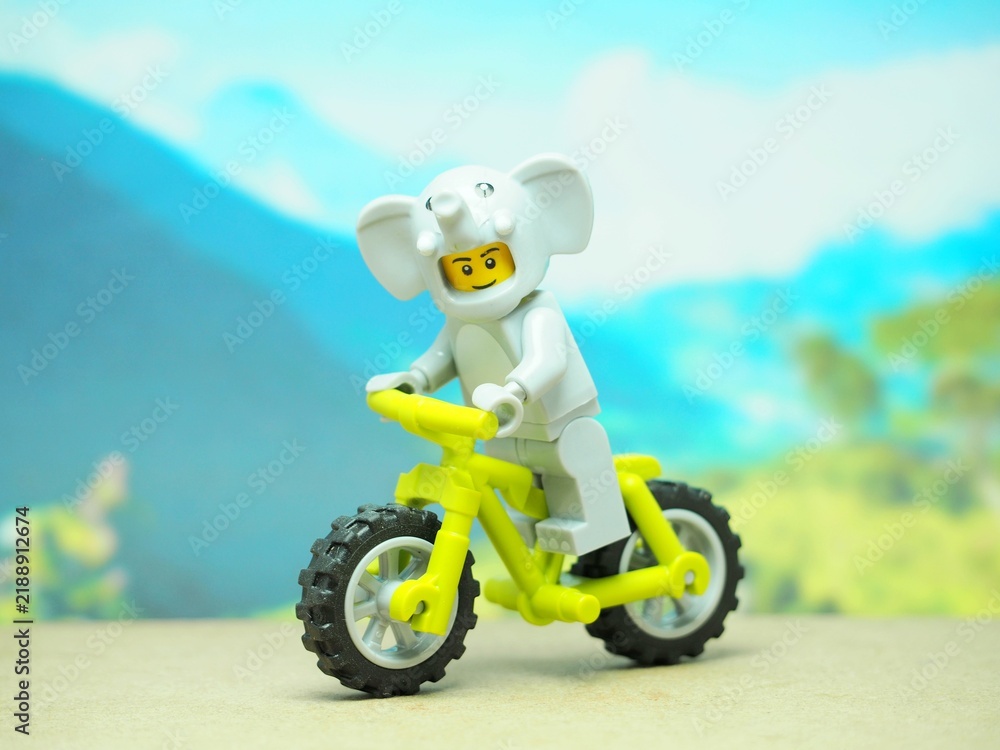 Fototapeta premium Indonesia - October 3, 2023 : Mini toy of action figure at table with blurred background. Toy photography concept. Riding the bicycle conceptual design.