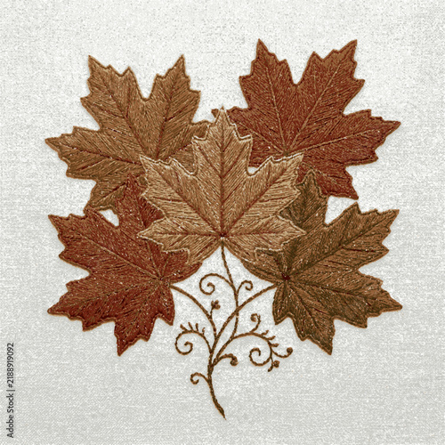 A cluster of finely detailed embroidered brown maple leaves with elegant swirling stems on fabric with intricate thread embroidery