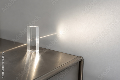 Sunbeam passing through clear acrylic block onto white wall, light transmittance concept