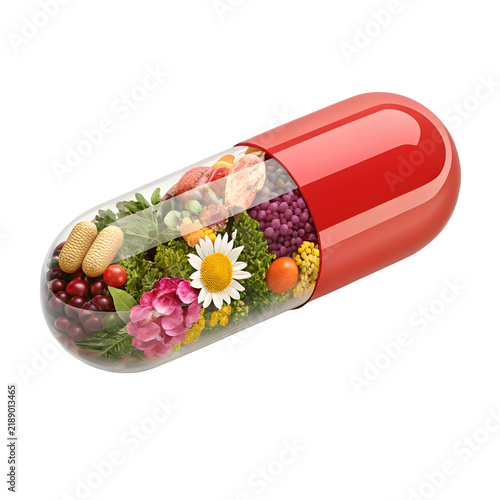 Nutritional supplement capsule filled with assorted fresh fruits vegetables and flowers on a white studio setting