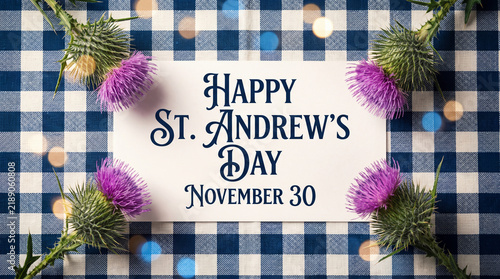 A festive greeting card for St. Andrew's Day on November 30th, decorated with purple Scottish thistles on a blue and white checkered background with bokeh.
