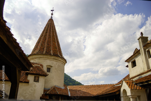 Foto Bran Castle, Romania, with its distinctive conical roof tower and tiled roofs, under a cloudy sky
