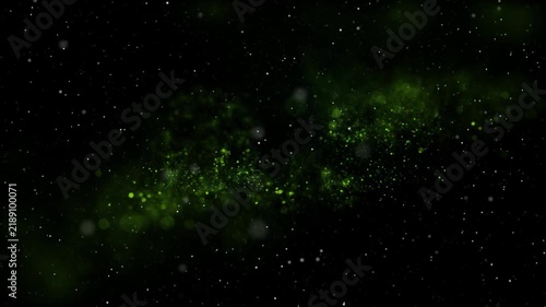 Green glowing particles scatter across deep space like a luminous cosmic dust cloud on a black background.