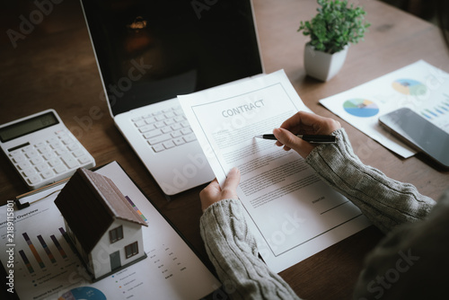 A real estate professional reviews and signs a property agreement, representing a home purchase, mortgage approval, investment, and legal transaction.