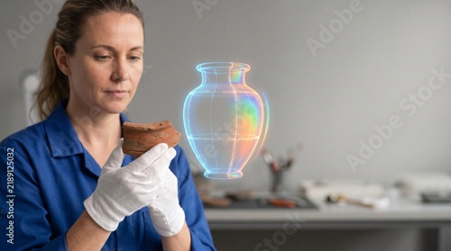 Archaeologist holding terracotta artifact fragment next to holographic 3D reconstructed urn in conservation lab