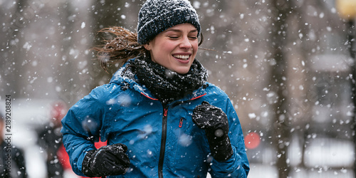 A young woman smiles as she runs through a snowstorm, dressed warmly in winter gear.