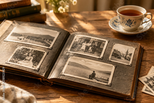 Open photo album with old black-and-white photos and tea, retrospect and nostalgia concept