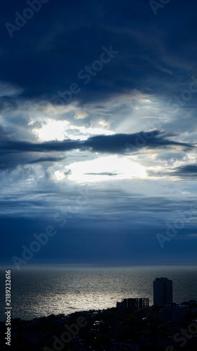 Картината върху платно dramatic crepuscular rays breaking through dark storm clouds over ocean, vertica