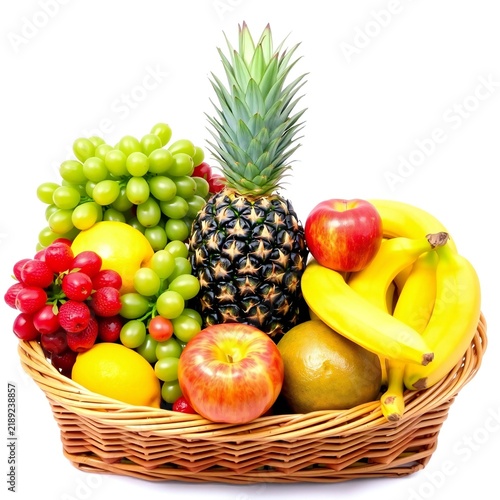 Fresh mixed fruits in a woven wooden basket including pineapple, bananas, grapes, and apples
