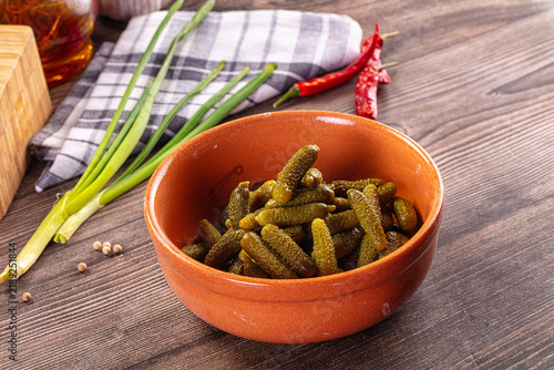 Obraz na plátně Pickled gherkins in rustic terracotta bowl with green onions, red chili peppers,