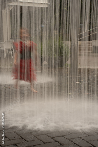 Foto blurred figure in a red dress walking barefoot behind cascading vertical water s