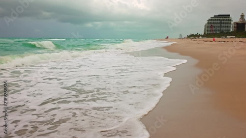 Beautiful view of stormy Atlantic Ocean waves rolling onto Miami Beach with beachfront hotels.