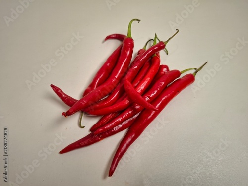 Foto Fresh long red chili peppers arranged in a pile on a clean, neutral background with copy space