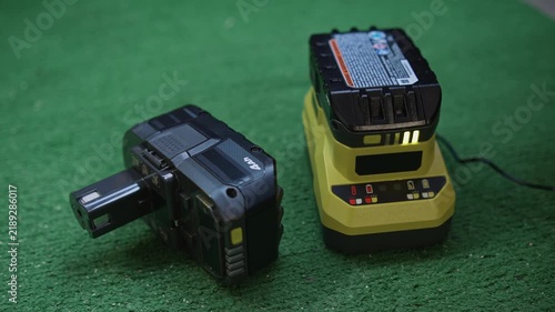Man inserting battery into power tool charger close up showing process of battery installation and start of charging on working surface
