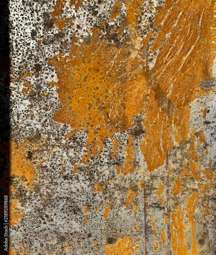 Abstract background of bright orange rust and dark corrosion spots on a weathered metal surface.