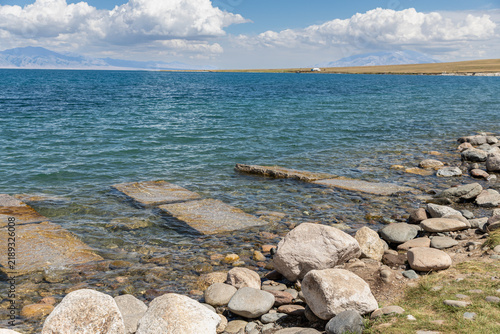 Fotografía Rocky shoreline of Sayram Lake under blue summer sky