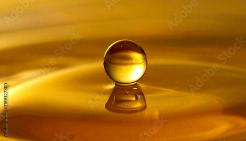 Golden Droplet on Molten Gold Surface: A perfect, spherical droplet of golden liquid suspended above a rippling surface of molten gold, creating a mesmerizing and luxurious visual.