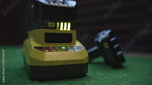 Close up power tool battery charging on charger with level indicator lights showing charging process and energy level on working surface