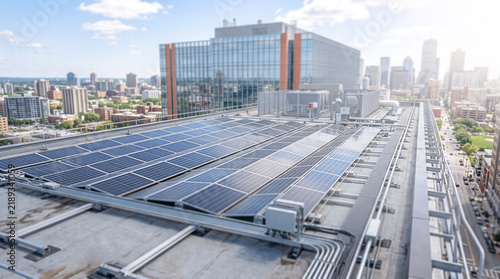 High angle view of solar panels on a modern urban building roof with city skyline in background, concept of renewable energy and sustainable city development