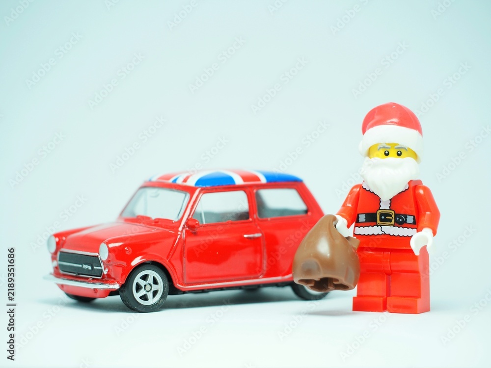 Obraz premium Indonesia - September 11, 2023 : Mini toy at table with blurred background. Oldman Santa Claus carrying gift concept design.