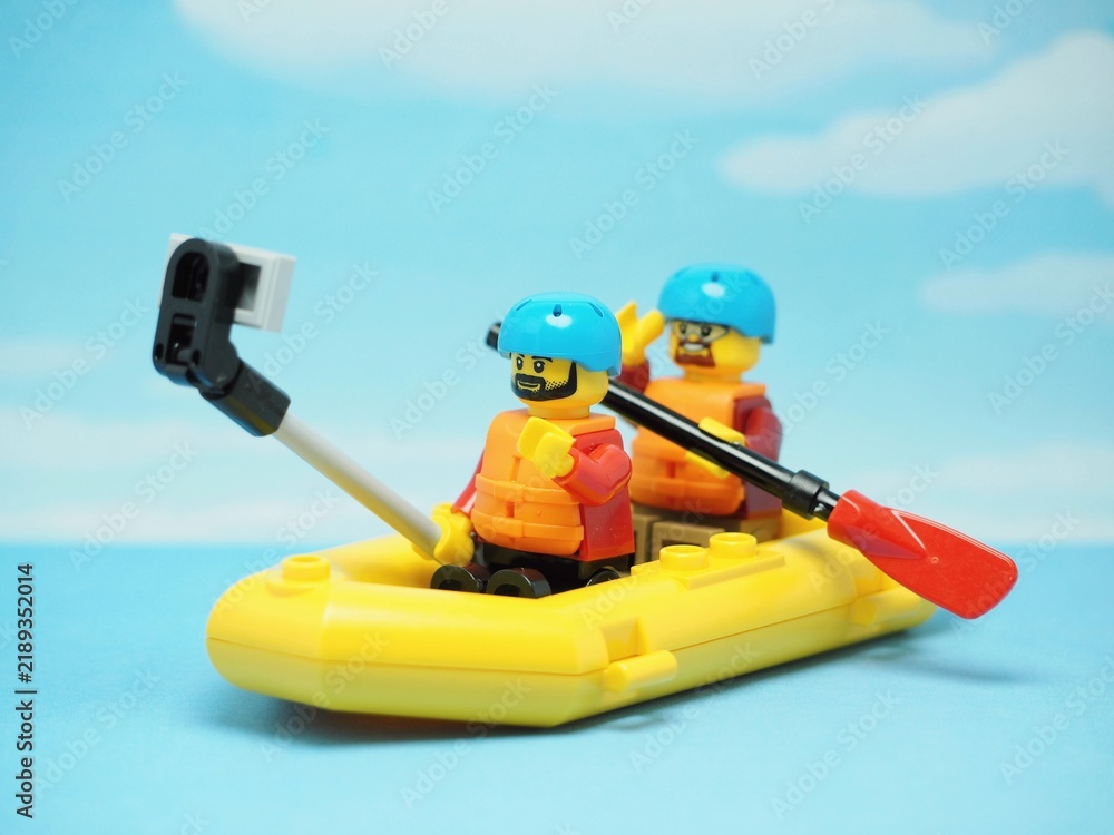 Obraz premium Indonesia - May 10, 2023 : Mini toy of action figure at table with blur background. Miniature photography concept design. Minifigure of people character with inflatable rubber boat and selfie camera.